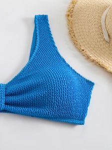 Detail of blue bikini top featuring wavy textured fabric and summer straw hat decor