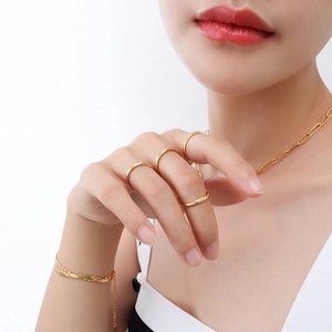 Polished rose gold stainless steel jewelry set with rings, necklace, and bracelet on model