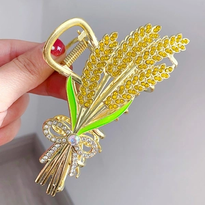 Detailed close-up of golden wheat ear hair claw clip with enamel leaves and rhinestones