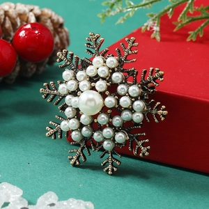 Macro shot of vintage bronze snowflake brooch with pearl accents on festive background
