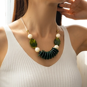 Macro detail of bohemian layered necklace with green acrylic beads and white pearls
