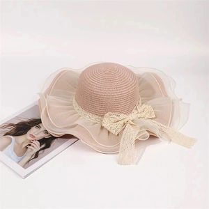 Detail of pink straw sun hat featuring lace bow, organza ruffle and wide wavy brim