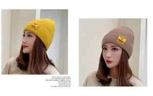 Detail showing knit texture and MOMENT OF AMBITIONS label on warm winter beanie