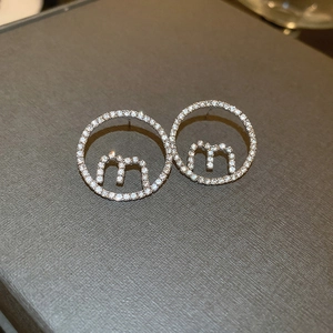 Macro shot of silver bow pearl tassel earring with crystal-inlaid 'm' letter detail