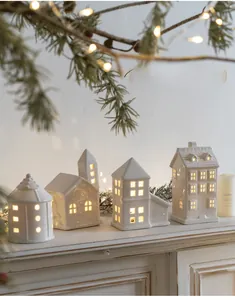 Detailed view of four white ceramic Christmas house lanterns with warm LED light glow