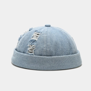 Detailed view of light blue distressed denim brimless cap with ripped street style textures