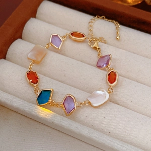 Détail d'un bracelet vintage doré avec breloques en nacre colorée dans un écrin