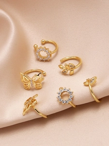 Detailaufnahme von 6 goldenen Ohrmanschetten mit Schmetterlingen und Zirkonia auf Satin
