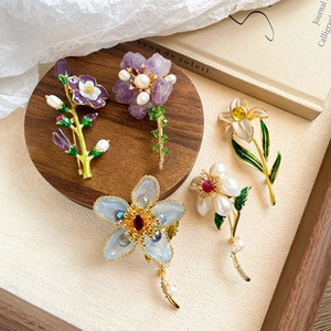 Macro shot of assorted enamel floral brooches with pearls and crystals on a wooden tray