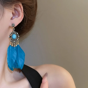Détail de boucles d'oreilles bohèmes avec plumes bleues et pierre turquoise vintage