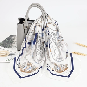 Sciarpa di seta con stampa nautica blu e bianca appesa a una borsa a mano grigia chic