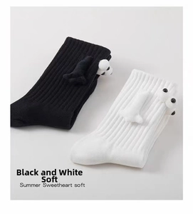 Detail of 3D plush cartoon eyes and arms on ribbed white and black cotton socks
