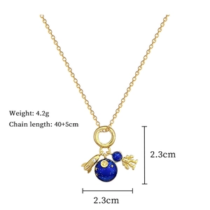 Detail of space-themed gold necklace with astronaut, blue enamel planet and rocket pendant