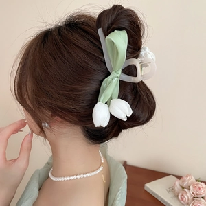 Detailed view of tulip hair claw with green satin bow worn in an elegant updo