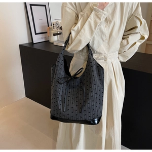 Detail of grey vertical striped knit tote bag with bow tie on a minimalist studio set