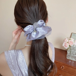 Detail of lilac silk bow hair tie with pearl pendant worn on a ponytail hair