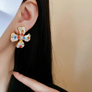 Detail of vintage gold clover earring with white enamel, pearls and colorful rhinestones