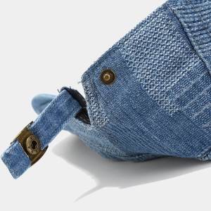 Detail of adjustable bronze metal buckle and washed denim texture on retro blue flat cap