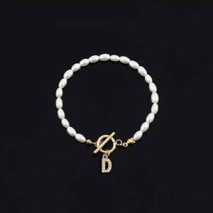 Elegant white oval pearl bracelet featuring a gold letter D charm and OT toggle clasp