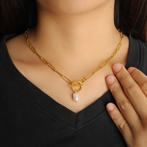 Collana in acciaio dorato con chiusura OT e ciondolo di perla indossata da modella