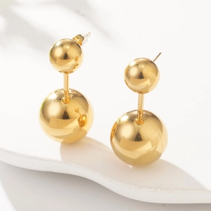 Detailed view of golden double ball stud earrings on white display with soft shadows