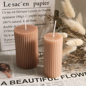 Detalle de dos velas de pilar estriadas en colores café y crema para decoración