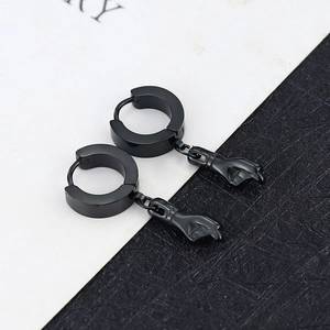 Detail of punk style black titanium steel hoop earrings with unique hand pendant charms