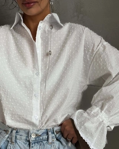 Detail of white cotton blouse showing polka dot jacquard fabric and ruffled lace cuffs