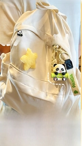 Detail of cute resin panda keychain with bamboo and yellow star on a white backpack