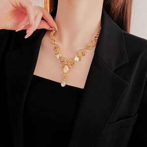 Dettaglio della collana a goccia dorata con cristalli lucenti sul collo femminile