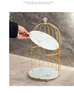 Detail showing removable marble pattern tray from golden birdcage cosmetic organizer