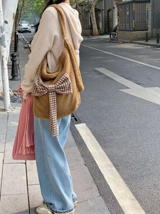 Street style shot of a brown plush crossbody bag with a houndstooth bow detail