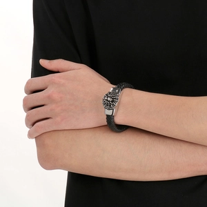 Détail d'un bracelet pour homme en cuir tressé avec crâne argenté et motifs de toile d'araignée