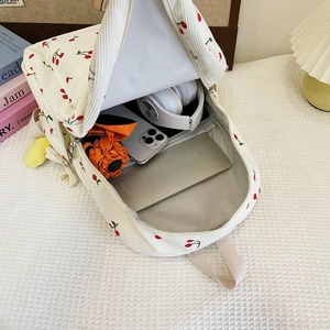 Top view of open corduroy cherry backpack showing spacious interior with laptop and gear