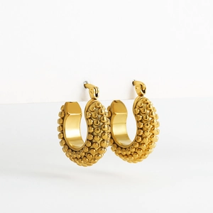 Detail view of gold hollow hoop earrings with textured bead pattern and secure latch closure