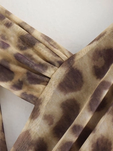 Detailed macro shot of the leopard print mesh fabric texture with translucent weave pattern