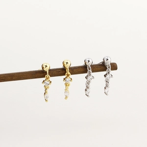 Macro shot of long s925 silver dangle earrings with sparkling diamonds in gold and silver