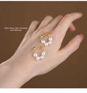 Close-up of S925 silver U-shaped earrings with five lustrous white pearls on hand