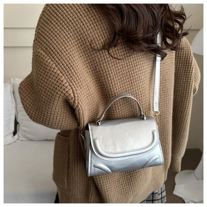 Detailed view of silver metallic textured crossbody bag with elegant curved stitching