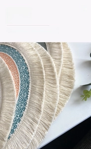 Close-up of bohemian woven cotton coaster with geometric patterns and fringe tassels