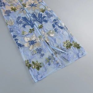 Detailaufnahme des hellblauen Netzkleids mit Blumenstickerei und glänzenden Pailletten