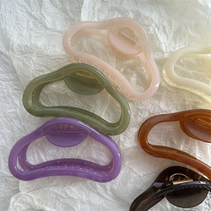 Flat lay of large hollow hair claws in six pastel colors with golden metal springs