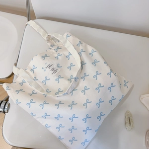 Detailed close-up of light blue ribbon floral pattern on off-white canvas tote bag