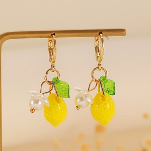 Close-up of yellow lemon drop earrings with green leaves and pearl flower details