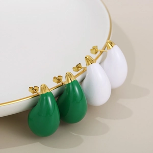 Detail of water drop earrings in green and white enamel on a white porcelain plate