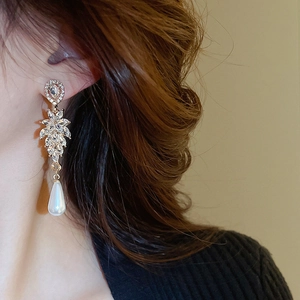 Detail of elegant leaf earrings with sparkling rhinestones and white teardrop pearls