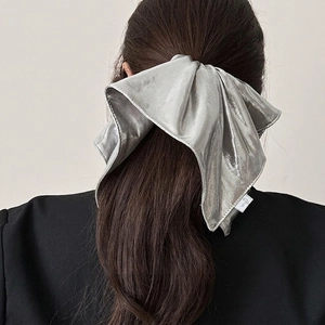 Silver metallic oversized scrunchie bow tied on brunette hair for elegant styling