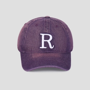 Détail d'une casquette en coton lavé violet avec la lettre R brodée en blanc en relief