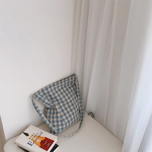 Détail d'un sac cabas en toile à carreaux bleu et blanc avec bandoulière au style épuré