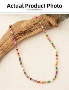 Detailed close-up of colorful natural stone beaded necklace with white pearls on wood